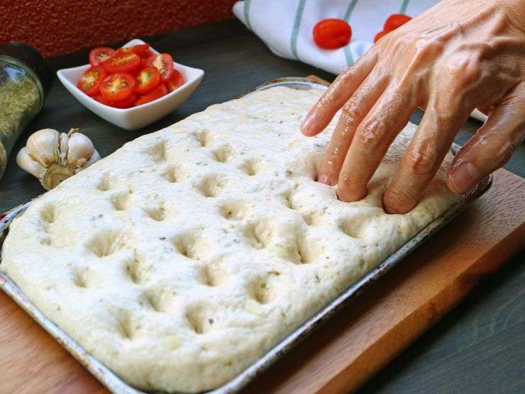 uomo che prepara focaccia genovese in casa