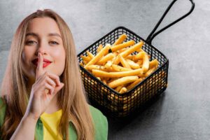 donna che fa segno di un segreto e patatine fritte dentro cestello dietro